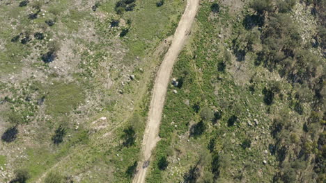 Dirt-path-winding-through-hill-in-Portuguese-Northern-Minho-Mountains---Aerial-Birds-eye-view-shot