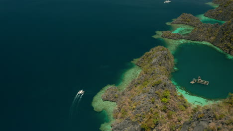 Toma-Aérea-Siguiendo-Un-Bote-Estabilizador-Cerca-De-Una-Isla-Tropical-Desierta-En-El-Nido,-Palawan,-Filipinas