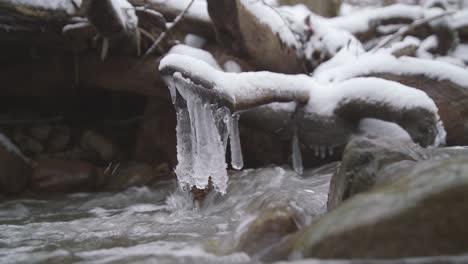 Eis,-Das-An-Einem-Stock-über-Fließendem-Wasser-Hängt