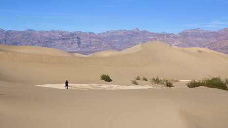 Lonely-person-walking-alone-down-a-huge-sand-dune-in-the-desert