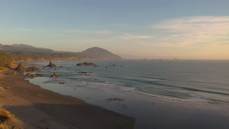 People-Enjoy-Sunset-At-The-Beach-In-Port-Orford,-Oregon-Coast---Aerial-drone-shot