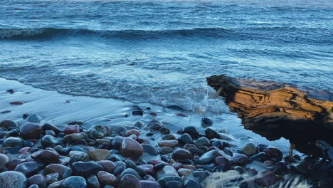 Runde-Und-Glatte-Steine,-Die-Von-Schäumenden-Wellen-An-Der-Küste-Umspült-Werden