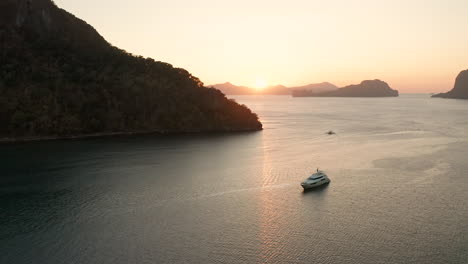 Aerial-showing-a-big-yacht-with-sunset-in-the-harbor-of-El-Nido,-Palawan,-Philippines