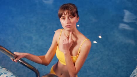 Hübsches-Junges-Mädchen-In-Einem-Gelben-Badeanzug-Im-Pool-Lächelnd