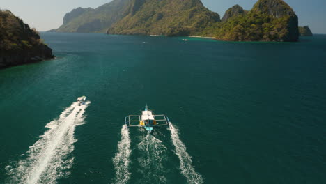 Aerial-tilt-down-showing-speedboat-and-outrigger-boat-in-El-Nido,-Palawan,-Pilippines