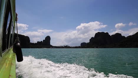 Sunny-day-riding-in-a-green-speed-boat-surrounded-by-ocean-water-and-rock-mountains-in-Southeast-Asia