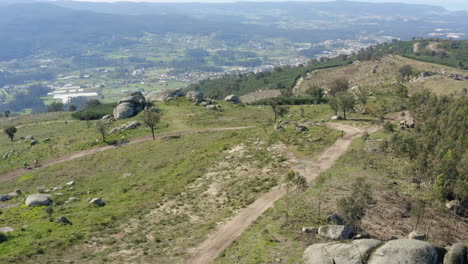 Uphill-trail-being-climbed-by-group-Mountain-Bikers-in-Minho,-Portugal---Aerial-Fly-over-meet-tracking-shot