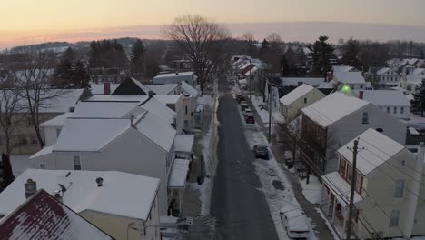 Aerial-establishing-shot-of-old-homes-in-winter-snow-along-quiet-empty-street