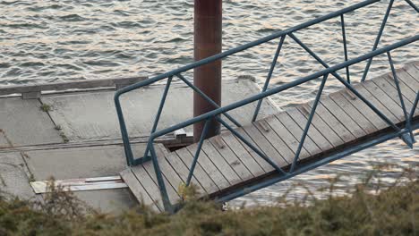 Small-wooden-waterfront-gangway-platform-floating-on-shiny-river-ripples