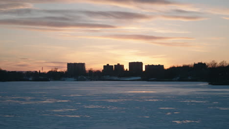 Silhouetted-City-With-Frozen-Lake-Of-Nations-In-Sherbrooke,-Quebec,-Canada-During-Sunset