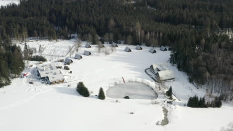 Aerial-Shot-Of-Winter-Ski-Camp-In-A-Alpine-Mountain-Landscape-During-Winter,-Snow-Covered