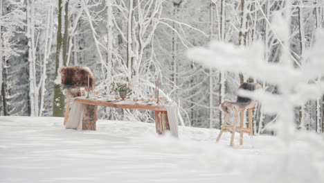 Wedding-editorial-setting,-decorated-table-with-two-chairs-in-snowy-winter-forest