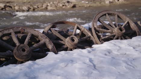 50-FPS-Three-Rotten-Ancient-Museum-Wagon-Wheels-Placed-near-the-Flowing-River