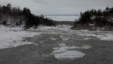 Menschen,-Die-Eine-Brücke-über-Einem-Eisigen-Strom-In-Rutschen-überqueren-Chaudiere-Kanada---Luftaufnahme