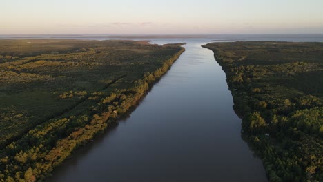 Aerial-high-shot-of-long-Amazon-River-at-sunset-with-large-rainforest-at-the-sides-4K