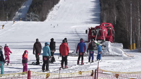 Rotes-Pistenfahrzeug,-Das-Eine-Gruppe-Von-Skifahrern-In-Richtung-Einer-Skipiste,-Tschechien,-Schleppt