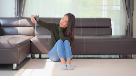 A-pretty-woman-sitting-on-the-floor-tries-several-angles-for-just-the-right-selfie