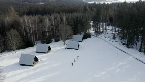 Toma-Aérea-De-Gente-Esquiando-En-Un-Campamento-De-Esquí-De-Montaña-De-Invierno,-Deporte-De-Nieve-Recreativo-De-Ocio