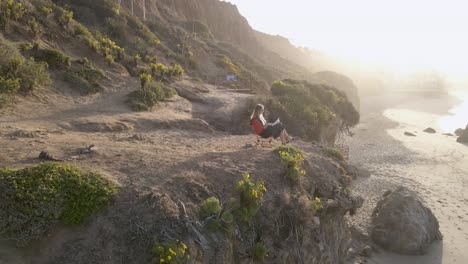Blond-caucasian-woman-reads-book-sitting-in-front-of-El-Matador-beach,-California