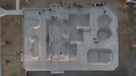 Aerial-view-above-people-biking-in-a-skate-park,-sunset-in-California---Top-down,-drone-shot