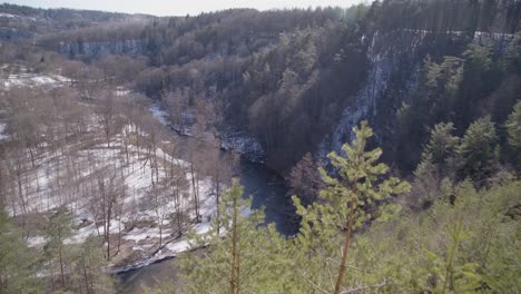 Wide-Shot-of-River-Running-in-a-Forest-Valley-on-a-Bright-Winter-Day-in-Vilnius