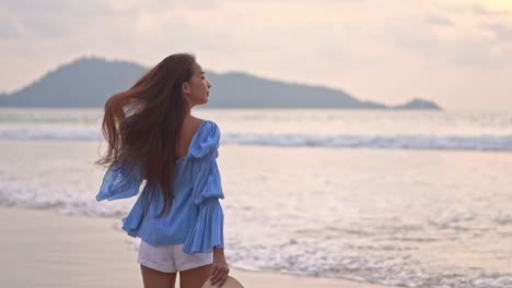 A-young-pretty-woman-walking-along-the-beach-into-the-surf