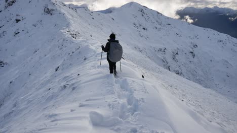 Woman-hiker-crosses-a-snowy-ridge-in-high-altitude-in-the-kepler-track-in-New-Zealand,-Fiordland