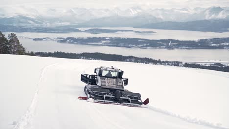 Snowcat-driving-over-large-snow-covered-mountains,-preparing-the-slopes