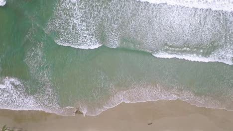 From-the-top-view-of-a-light-blue-sea-breaking-in-a-sandy-beach