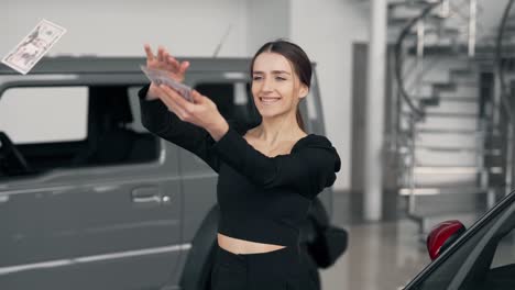 Happy-young-woman-scattering-money-in-a-car-dealership