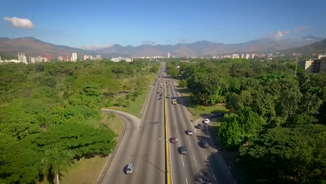 From-the-top-view-of-a-highway-in-Valencia,-Carabobo,-Venezuela,-next-to-a-green-park