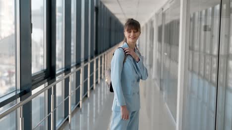 Stilvolles-Junges-Mädchen-In-Einem-Blauen-Business-Anzug-Mit-Handtasche-Posiert-Vor-Der-Kamera-In-Einem-Glasflur