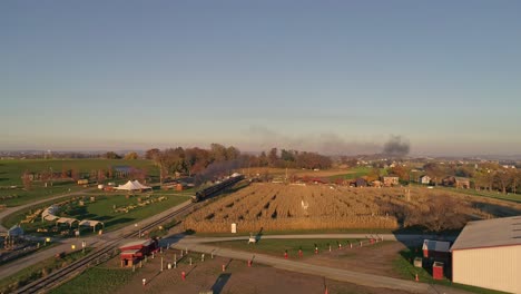 Aerial-View-of-an-Antique-Steam-Locomotive-Approaching-Pulling-Passenger-Cars-and-Blowing-Smoke-and-Steam-During-the-Golden-Hour-in-late-Afternoon