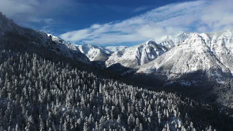 Majestic-Winter-Landscape-Scenery,-Sunny-Snow-Capped-Peaks-and-Conifer-Forest-on-Sunny-Day,-Drone-Aerial-View