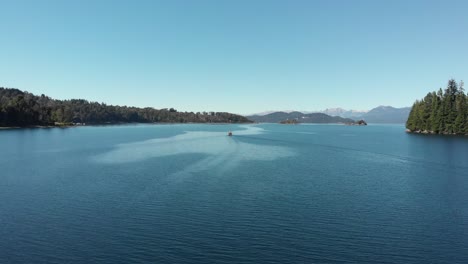 Die-Antenne-Des-Blauen-Himmels-Folgt-Dem-Segelboot,-Das-Auf-Dem-Tiefblauen-Patagonischen-See-Fährt