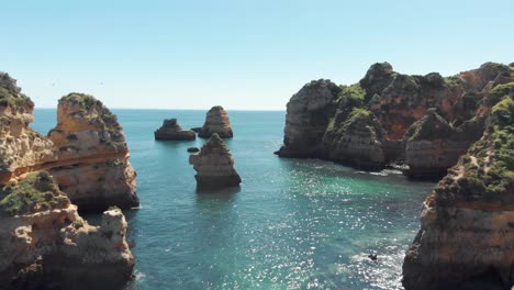 Scharfe-Felsen-Aus-Algarve-kalkstein,-Die-Aus-Dem-Türkisfarbenen-Meer-In-Lagos,-Portugal,-Auftauchen---Luftaufnahme