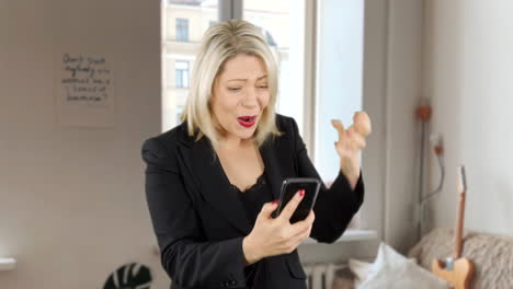 Attractive-blond-business-woman-angry-and-updet-as-she-loses-money-on-a-game-app-on-her-phone
