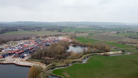 A-drone-shot-flying-over-the-small-town-next-to-Connington-Lake-feeding-off-the-Stour-River,-in-England