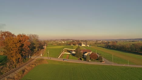 Luftbild-Eines-Pferdewagens,-Der-Sich-Einem-Bahnübergang-Mitten-In-Der-Amish-Landschaft-Und-Einem-Sonnigen-Tag-Nähert