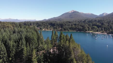 Rising-aerial-reveals-Manzano-Resort-amid-forest,-lake,-and-mountains,-Villa-la-Angostura
