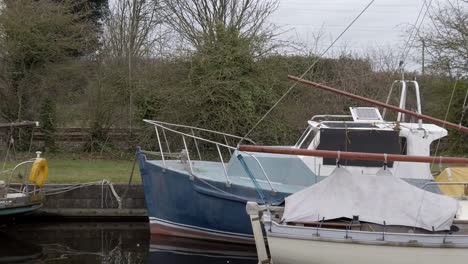 Small-sailboats-floating-on-narrow-rural-countryside-canal-marina