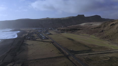 Seafront-Village-Of-Vik-At-Black-Sand-Beach-With-Rock-Mountainscape-In-Background-At-South-Iceland