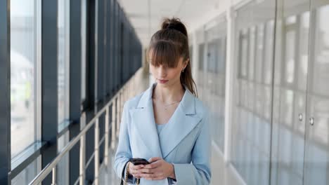 Stylish-girl-in-a-blue-suit-writes-in-a-smartphone