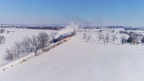 Aerial-View-of-an-Antique-Steam-Locomotive-Approaching-Pulling-Passenger-Cars-and-Blowing-Smoke-and-Steam-During-the-Golden-Hour-in-late-Afternoon