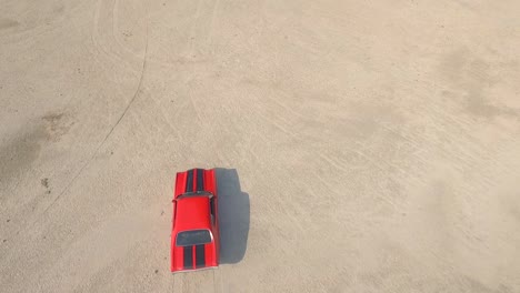 Birds-eye-from-the-top-view-of-an-old-American-muscle-car-in-a-desert-during-a-sunset