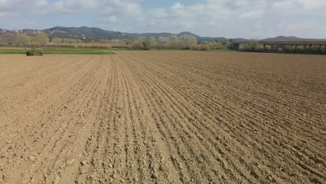 Low-Aerial-dolly-right-shot-of-plowed-field-prepared-for-cultivation