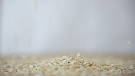 Oat-Flakes-Fall-in-Pile-in-Slow-Motion,-Close-Up-with-Copy-Space,-Side-View