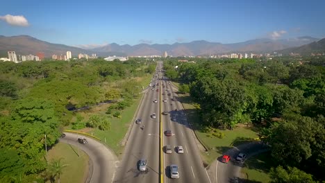 Drone-view-of-a-highway-in-Valencia,-Carabobo,-Venezuela,-next-to-a-green-park