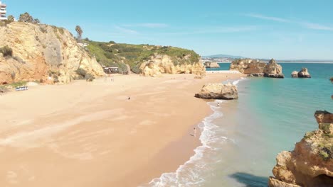 Touristen,-Die-Den-Dona-Ana-Strand-Genießen,-Der-Von-Den-Hängen-Der-Lagosküste-Ausgegraben-Wurde,-An-Der-Algarve,-Portugal---Luftfahrt-Mit-Niedriger-überführung