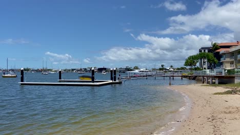 View-along-the-tranquill-shore-at-Maloolaba,-past-waterfront-perpaties-and-private-moorings